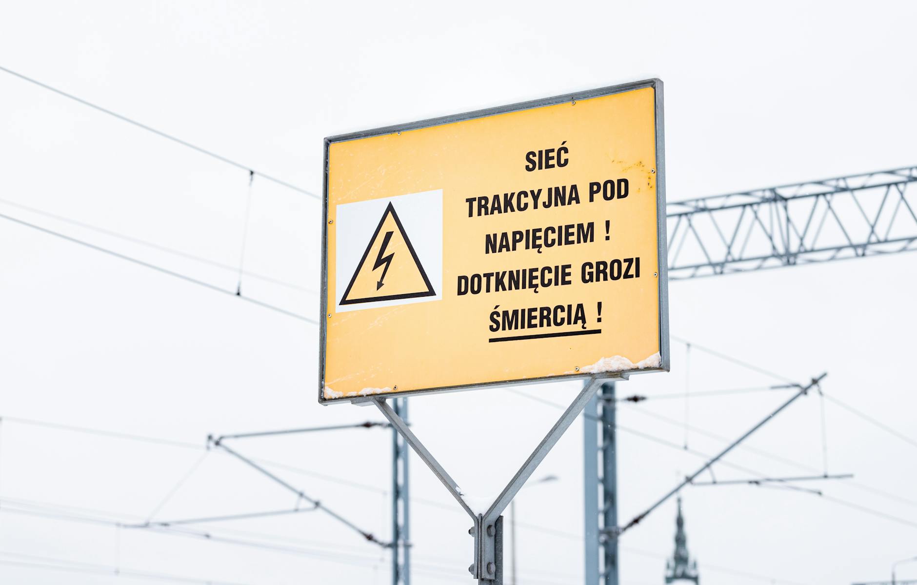 Znak drogowy informujący o objazdach i linie energetyczne symbolizujące potencjalne przerwy w dostawie prądu w Brzezinach.